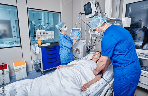 Staff nurses attending to patient in adult intensive care unit. ICU