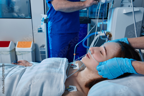 ICU. Staff nurses attending to female patient with oxygen nasal cannula in intensive care unit photo