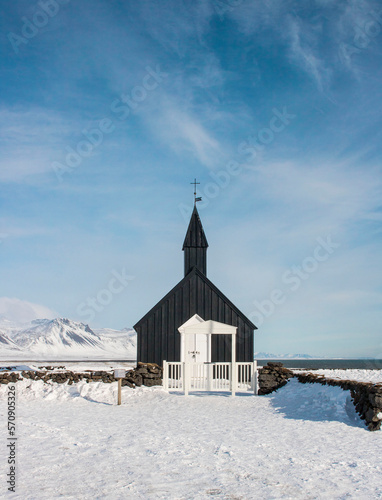 Snowy landscape of a black colored church in Iceland with blue sky