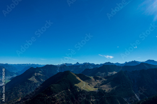 Panoramic view from the peak of a mountain towards the summits far away and the blue sky