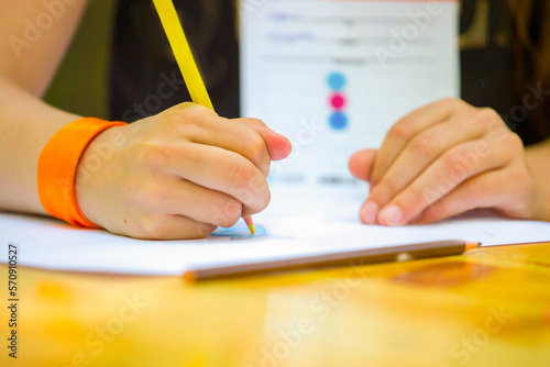 close-up of a child's hand drawing with colored pencils on a white sheet of paper