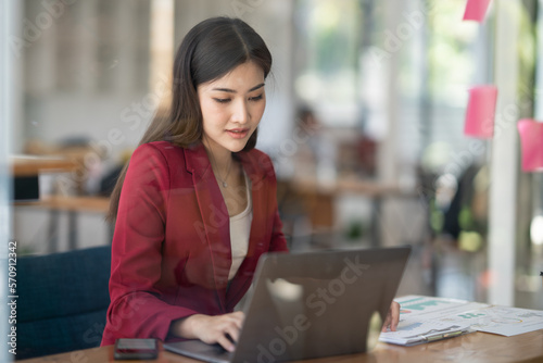 Charming Asian businesswoman using laptop computer while working in the company office room.