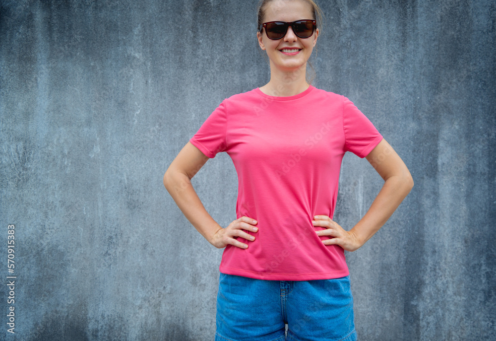 Female model wearing pink blank t-shirt on the background of an gray scratched wall. Female model wearing pink blank t-shirt on the background of an gray scratched wall.