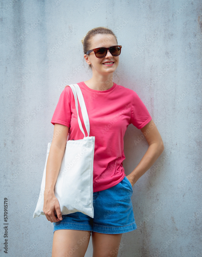 Female model wearing pink blank t-shirt on the background of an gray wall. Female model wearing pink blank t-shirt on the background of an gray wall.