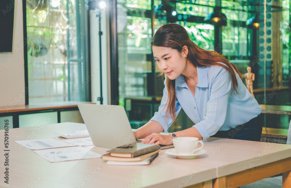 Asian business woman working using  laptop for do math finance on wooden desk, tax, accounting, statistics and analytical research concept