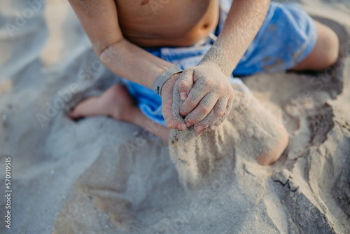 Little boy playing on the beach  sitting in a sand.