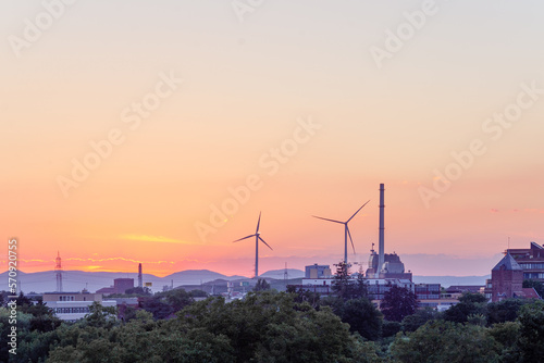 industrial zone with wind turbine and a pipe in the evening against the backdrop of hills