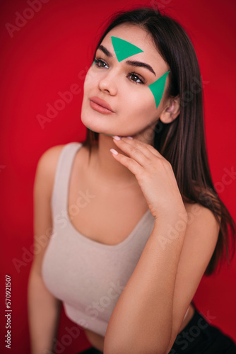 Kinesiotaping. a girl with a green kinesio tape on her face. the concept of facial care