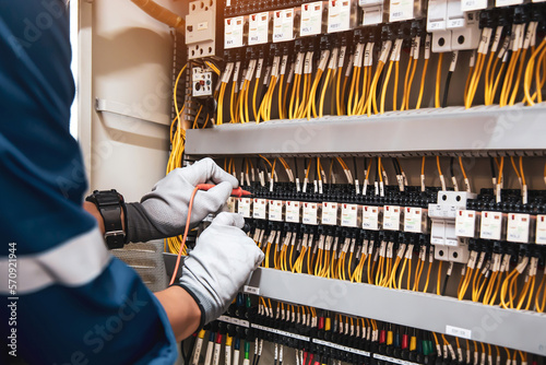 Electricity or electrical maintenance service, Electrician hand checking electric current voltage at circuit breaker terminal and cable wiring check in main power load center distribution board. photo