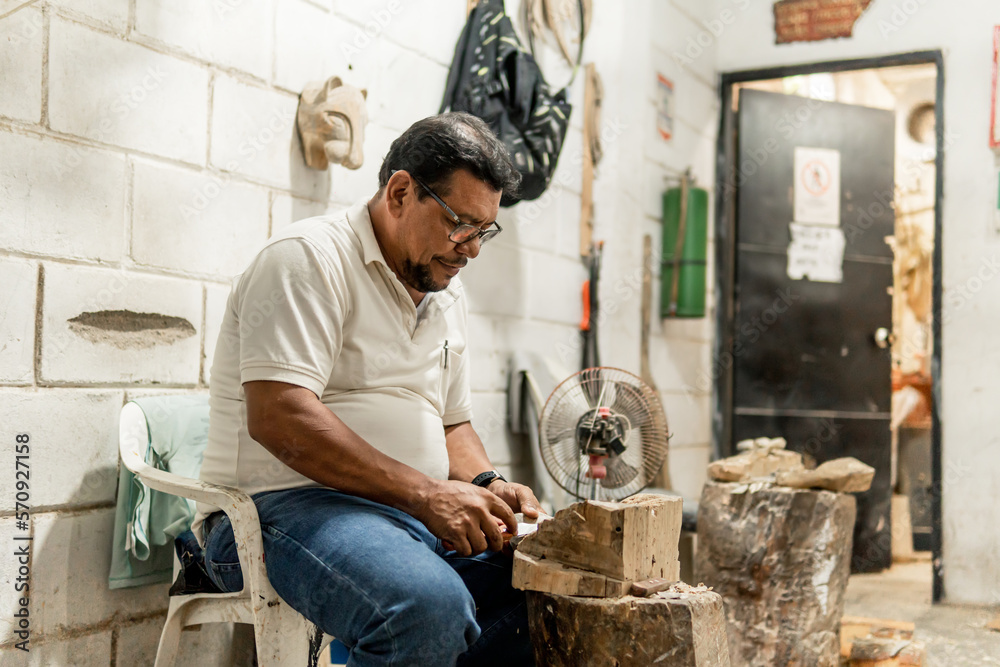 hands of older latino man carving a jaguar in wood with knife with a lot of passion hands of older latino man carving a jaguar in wood with knife with a lot of passion