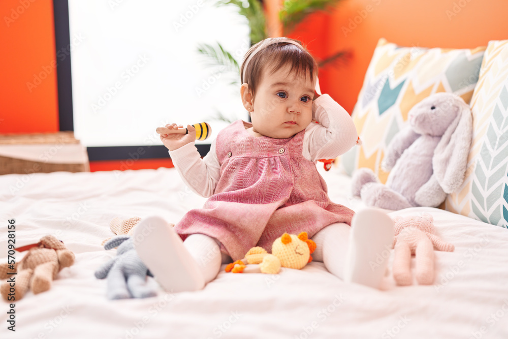 Adorable hispanic baby playing maraca sitting on bed at bedroom Adorable hispanic baby playing maraca sitting on bed at bedroom