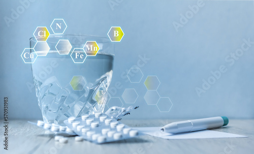 a glass of water, tablets, a pen.icons with microelement symbols. Supplements. health concept. Copy space