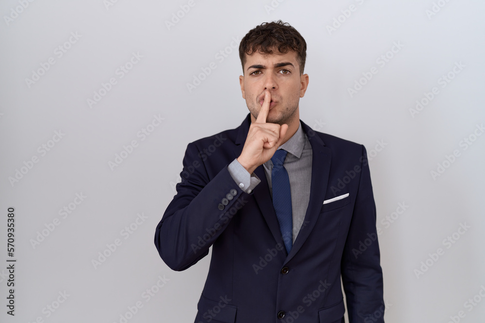 Young hispanic business man wearing suit and tie asking to be quiet with finger on lips. silence and secret concept. Young hispanic business man wearing suit and tie asking to be quiet with finger on lips. silence and secret concept.