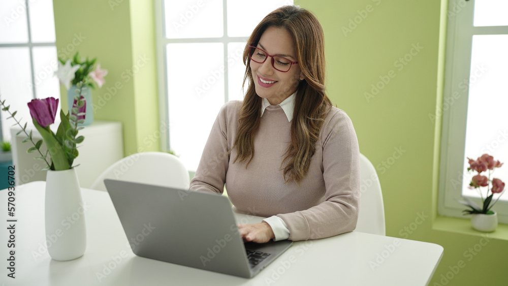 Young beautiful hispanic woman using laptop sitting on table at home Young beautiful hispanic woman using laptop sitting on table at home