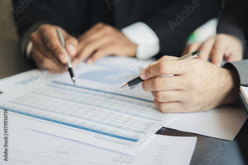 Close-up of two businessmen with pens pointing on report paper. Two Businessman discussing together in meeting room, investment projects.
