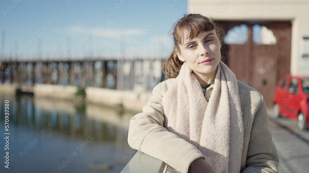 Young caucasian woman standing with serious expression at seaside