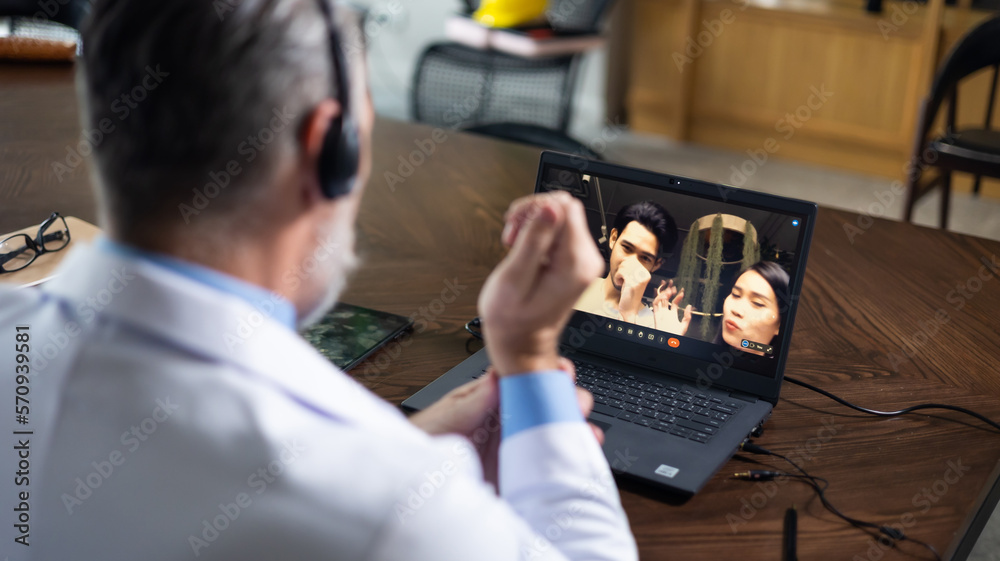 Back view. Senior caucasian doctor online video call conference with headset consult patient on laptop computer. Doctor online consultation and telehealth medicine Back view. Senior caucasian doctor online video call conference with headset consult patient on laptop computer. Doctor online consultation and telehealth medicine