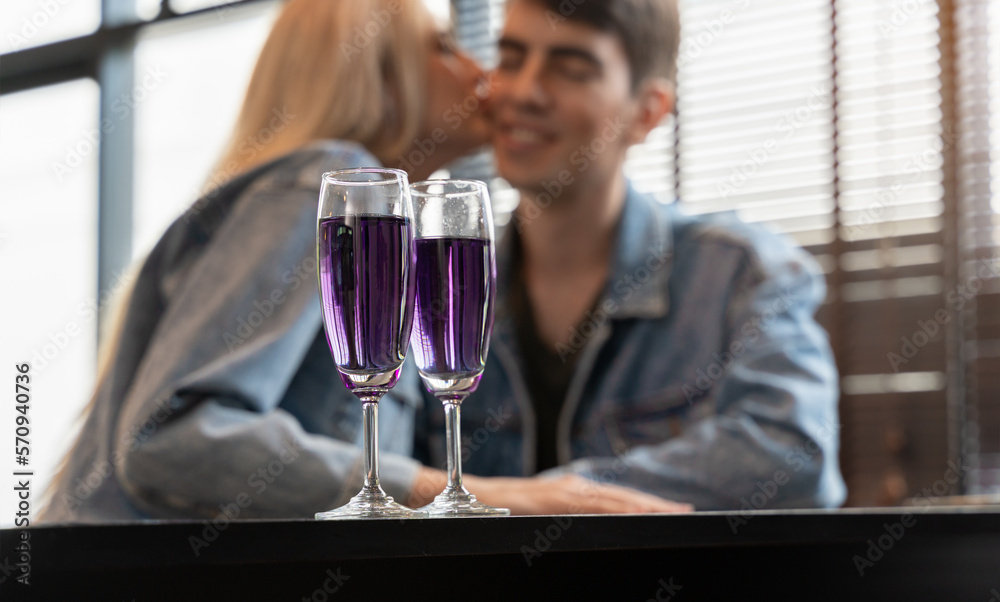 Glasses of purple cocktail with blurry happy loving couple at bar Glasses of purple cocktail with blurry happy loving couple at bar