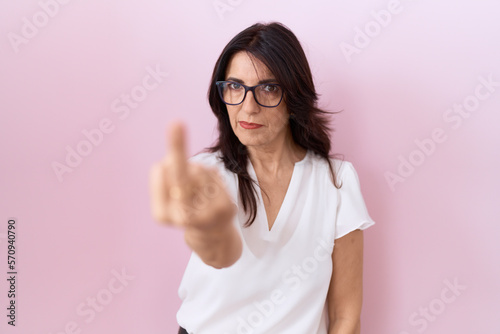 Middle age hispanic woman wearing casual white t shirt and glasses showing middle finger  impolite and rude fuck off expression
