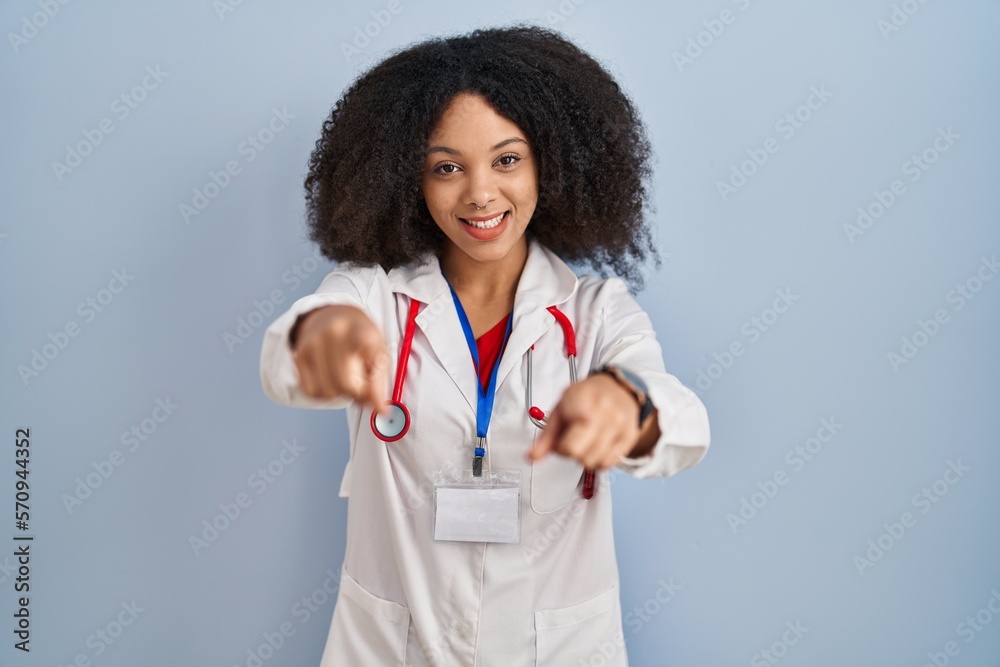 Young african american woman wearing doctor uniform and stethoscope pointing to you and the camera with fingers, smiling positive and cheerful Young african american woman wearing doctor uniform and stethoscope pointing to you and the camera with fingers, smiling positive and cheerful