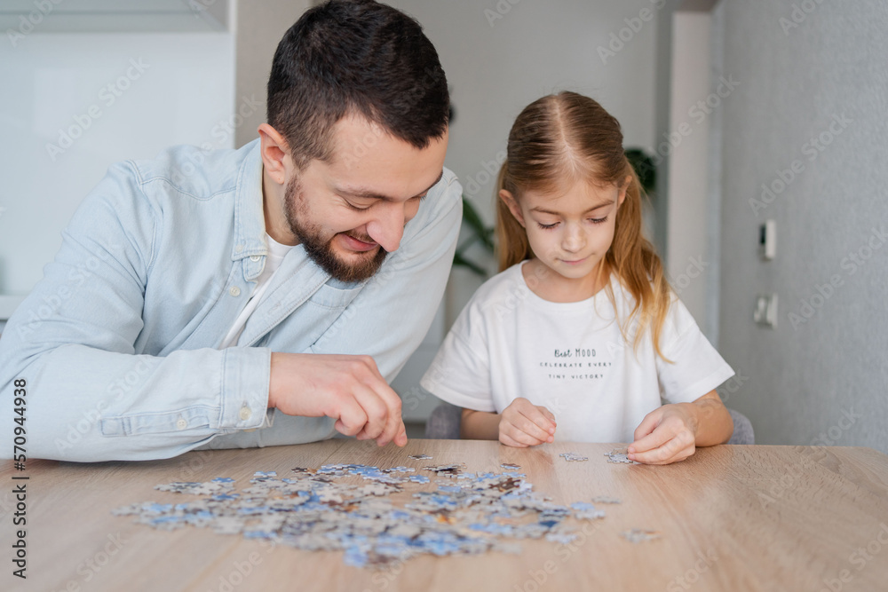 Fototapeta premium father and daughter playing with puzzles at home. Focus on man.