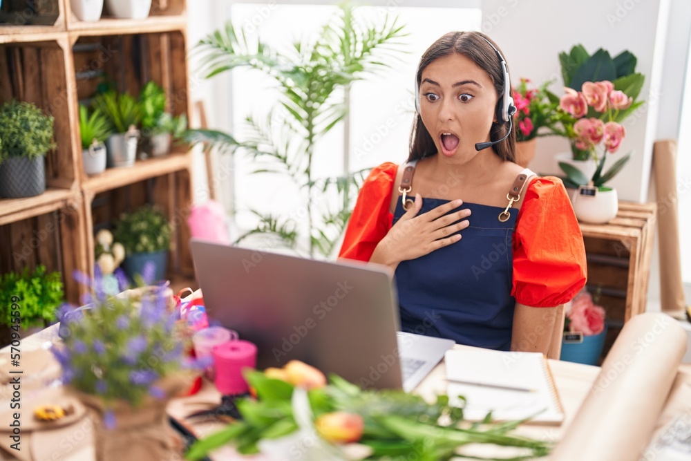 Young hispanic woman working at florist shop doing video call scared and amazed with open mouth for surprise, disbelief face