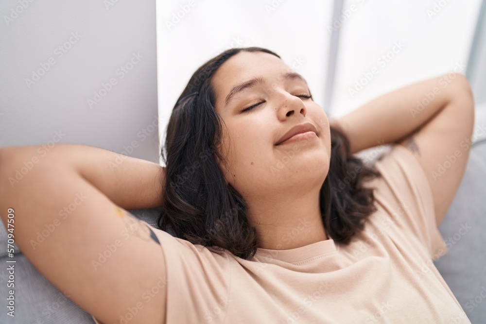 Young woman smrelaxed with hands on head sitting on sofa at home Young woman smrelaxed with hands on head sitting on sofa at home