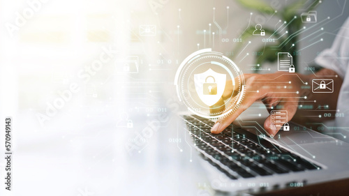 A businessman works on his laptop at home with a virtual display showing a symbol to signify cyber security privacy and online data protection