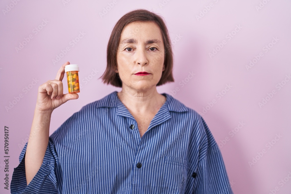 Middle age hispanic woman holding pills thinking attitude and sober expression looking self confident Middle age hispanic woman holding pills thinking attitude and sober expression looking self confident