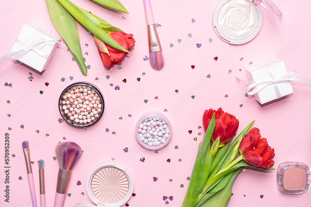 Bright festive spring composition with luxury make up products, brushes, red tulips and shining decorations on light pink background top view. Festive cosmetic sale and promo banner.