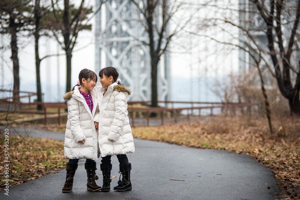 Two sibling dressed in winter clothe walking in the park Two sibling dressed in winter clothe walking in the park