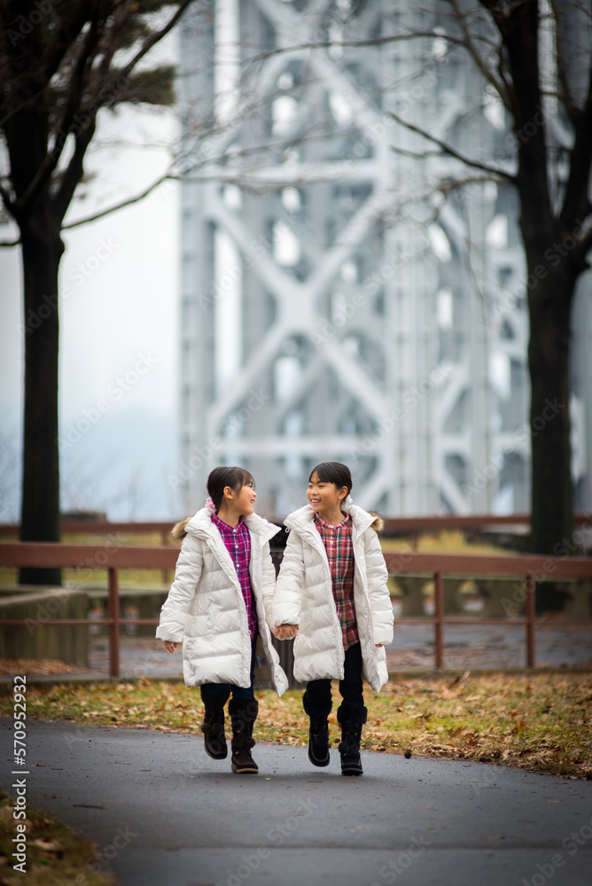 Two sibling dressed in winter clothe walking in the park Two sibling dressed in winter clothe walking in the park