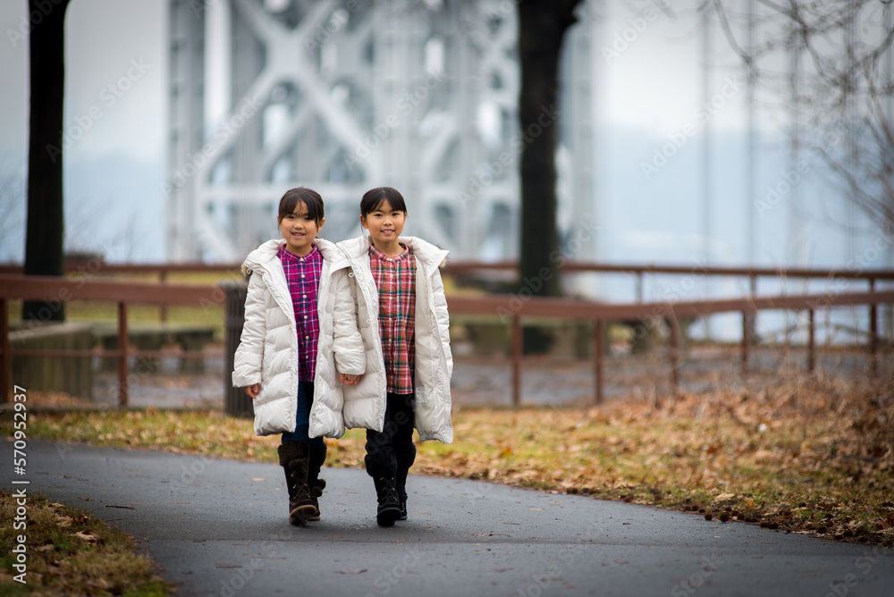 Two sibling dressed in winter clothe walking in the park