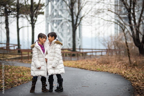 Two sibling dressed in winter clothe walking in the park © Naomichi