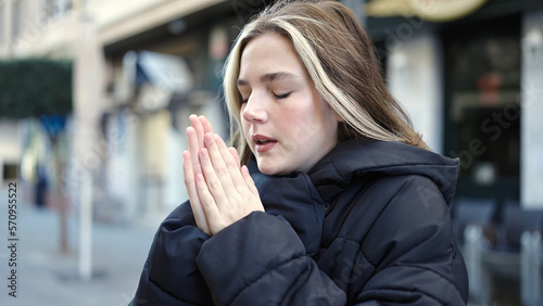 Young blonde woman rubbing hands for cold at street
