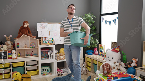 Young caucasian man working as teacher tidying up at kindergarten