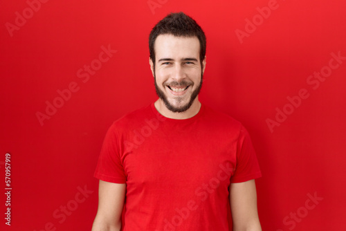 Young hispanic man wearing casual red t shirt with a happy and cool smile on face. lucky person.