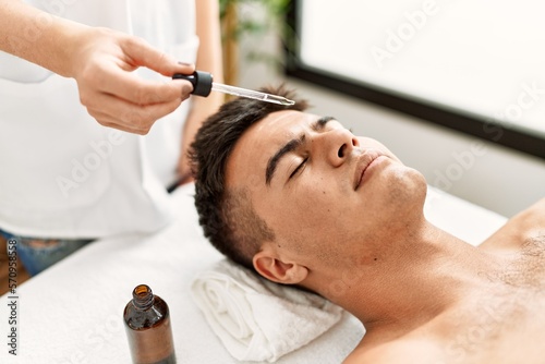 Young hispanic man relaxed having facial treatment at beauty center