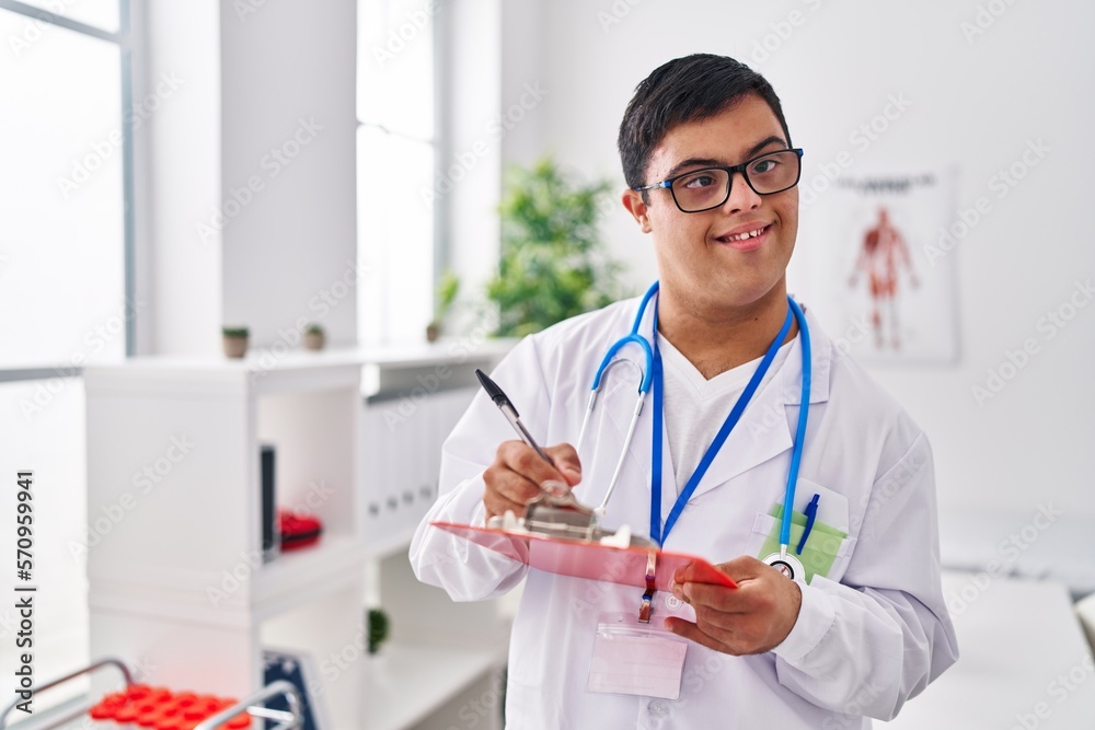 Down syndrome man wearing doctor uniform writing on document at clinic Down syndrome man wearing doctor uniform writing on document at clinic