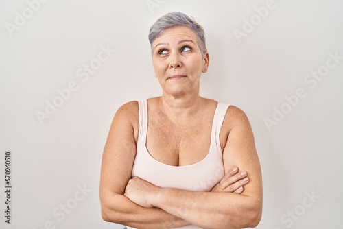 Middle age caucasian woman standing over white background smiling looking to the side and staring away thinking.