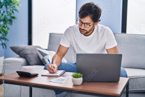 Young hispanic man using laptop working at home