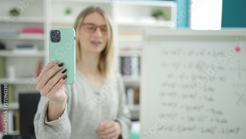 Young blonde woman recording teaching maths on magnetic board at library university