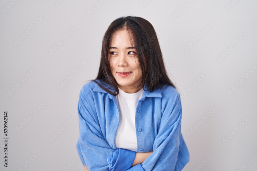 Young chinese woman standing over white background shaking and freezing for winter cold with sad and shock expression on face Young chinese woman standing over white background shaking and freezing for winter cold with sad and shock expression on face