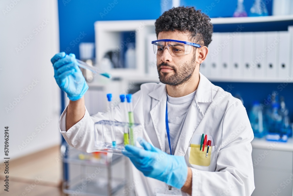 Young arab man wearing scientist uniform holding test tubes at laboratory Young arab man wearing scientist uniform holding test tubes at laboratory