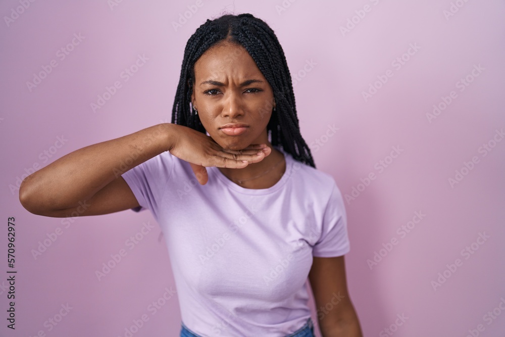 African american woman with braids standing over pink background cutting throat with hand as knife, threaten aggression with furious violence African american woman with braids standing over pink background cutting throat with hand as knife, threaten aggression with furious violence