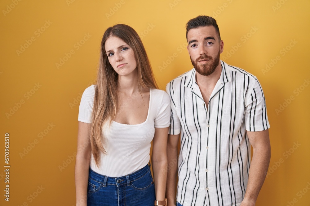 Young couple standing over yellow background looking sleepy and tired, exhausted for fatigue and hangover, lazy eyes in the morning. Young couple standing over yellow background looking sleepy and tired, exhausted for fatigue and hangover, lazy eyes in the morning.