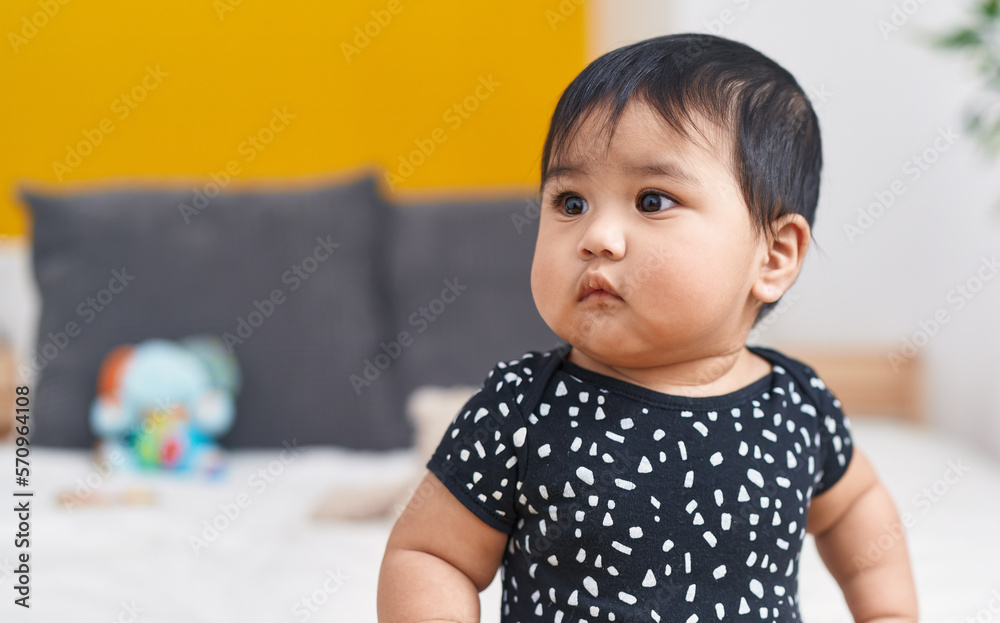 Adorable hispanic baby sitting on bed at bedroom Adorable hispanic baby sitting on bed at bedroom