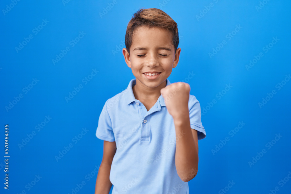 Little hispanic boy wearing casual blue t shirt celebrating surprised and amazed for success with arms raised and eyes closed