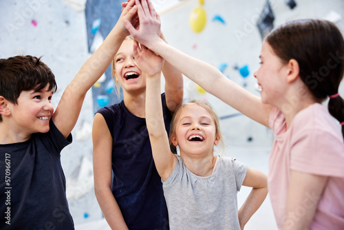 Little kids high fiving in a climbing gym