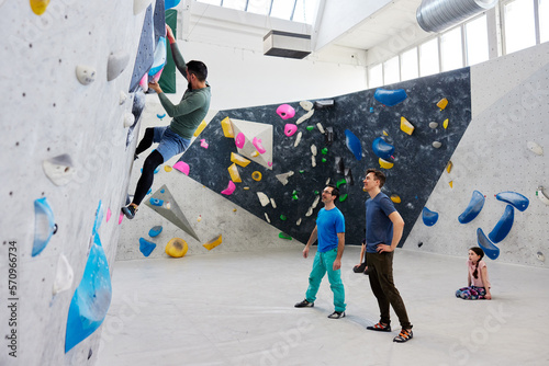 Men watching a friend climb in a bouldering gym
